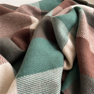 Close-up of soft woven plaid scarf fabric in green brown and beige with a wool-like texture