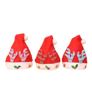Three red Christmas hats with plush reindeer antlers and holly leaf decorations on white