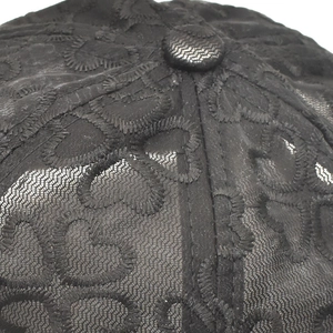 Detail shot of black lace baseball cap showing heart embroidery and mesh texture