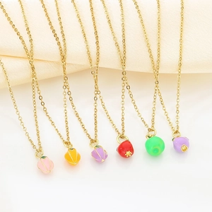 Colorful enamel fruit pendants on gold stainless steel chains over beige silk fabric