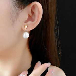 Boucles d'oreilles dorées en goutte avec un grand pendentif sphère blanc mat pour femme