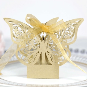 Detail of laser-cut golden butterfly candy box with pearlescent finish and ribbon bow