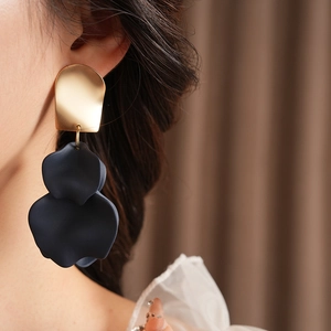 Close-up of a model wearing irregular gold and black petal-shaped textured earrings