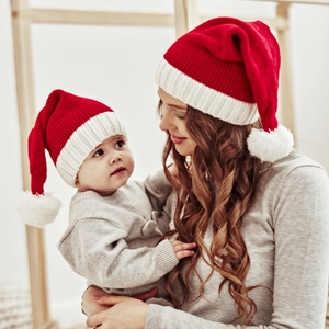 Close-up of matching grey knit beanies with faux fur pom poms for mother and child