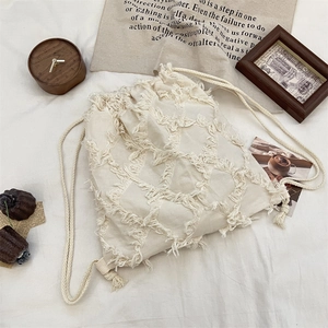 Detail of bohemian cream canvas backpack with fringe plaid texture and cotton drawstring