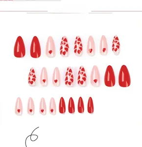Macro shot of almond-shaped pink and red press-on nails with sweet heart patterns