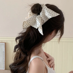 Detail of white polka dot bow scrunchie on dark wavy hair for a stylish look