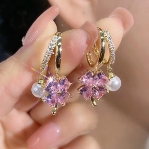 Detail of pink crystal clover earrings with hanging white pearls and gold accents