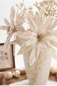 Detail of glitter champagne gold poinsettia and berry branches in a vintage vase