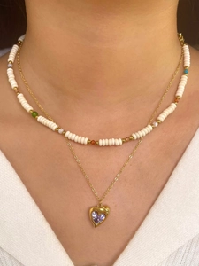 Detail of layered gold necklace set with white beads and a purple heart pendant