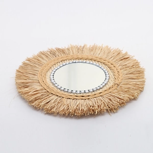 Handmade raffia wall mirror with boho fringe and silver bead trim on a clean white background