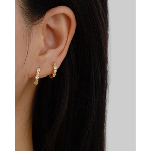 Elegant gold huggie hoop earrings with sparkling cubic zirconia on model's ear