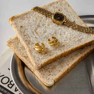 Creative lifestyle view of gold multi-layer ear cuffs and watch on rustic toast