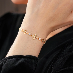 Gros plan d'un bracelet doré croix et fleur de lys avec zircon blanc sur un mannequin