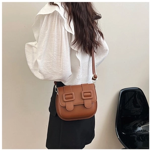 Sacoche vintage en cuir marron portée par un mannequin avec chemisier et jupe noire