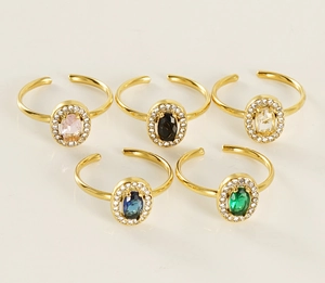Detail of adjustable gold-plated rings with colorful oval stones and zircon halo setting