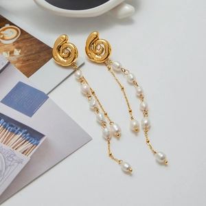 Detailed view of long gold tassel earrings with elegant white pearls and spiral metal studs