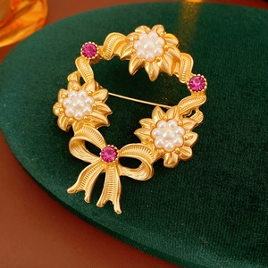 Detail of matte gold flower brooch with pink rhinestones and pearls on green velvet