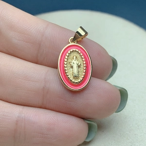 Golden oval Jesus pendant with pink enamel border and religious relief detail