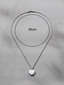 Détail du pendentif coeur en pierre blanche avec chaîne torsadée argentée de 30cm