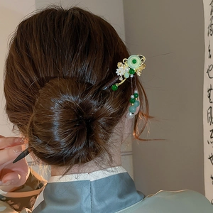 Detail of Chinese tassel hairpin with jade beads and white flowers in elegant hair bun