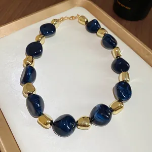Irregular blue marble acrylic and gold beaded necklace with lobster clasp in a tray