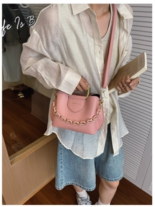 Pink PU leather bucket bag with gold handle and resin chain worn by a model