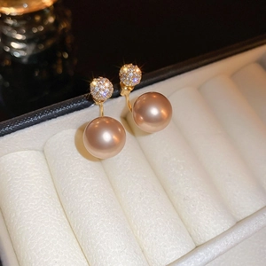 Close-up of elegant double-pearl earrings with sparkling gold rhinestones in a gift box