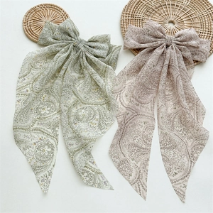 Detail of long ribbon bow hair clips with paisley print in light green and nude pink silk
