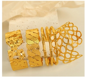 Detail of four 18k gold plated open bracelets with hammered, woven and bamboo textures