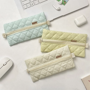 Quilted macaron pencil cases in mint, yellow, and beige with stationery and tech items