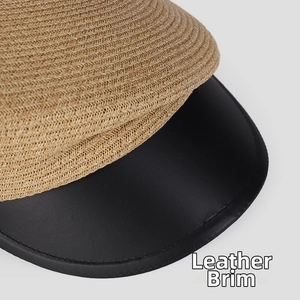 Close-up of woven straw texture with black leather brim on a stylish asymmetric hat