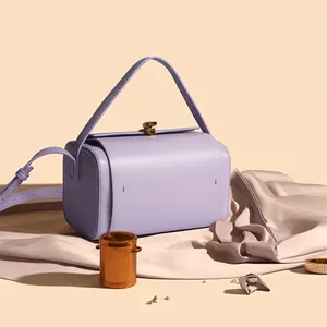 Sac Boston en cuir violet avec fermoir doré et bandoulière dans un cadre élégant