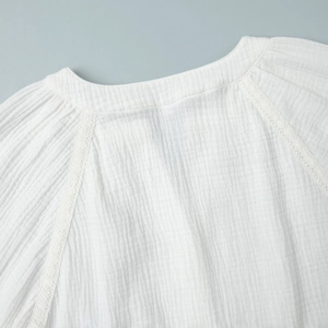 Dettaglio della camicia in cotone bianco stropicciato con pizzo delicato sulla cucitura