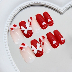 Red heart and bow cow print press-on nails with 3D accents on a heart mirror