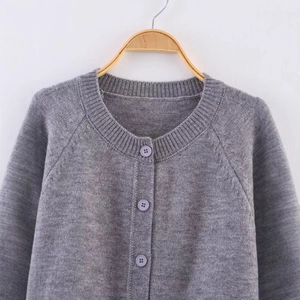 Minimalist grey knit cardigan with round neck and button front on a wooden hanger