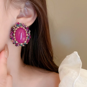 Close-up of a model wearing retro oval earrings with purple stones and colorful beads
