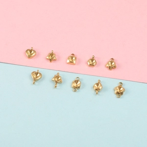 Variety of ten gold-colored stainless steel pendant base trays in diverse shapes on pastel background