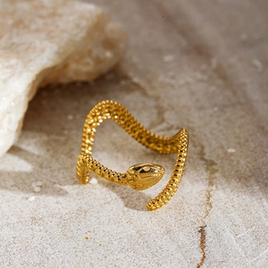 Detailed close-up of a golden punk-style snake-shaped open ring on textured stone