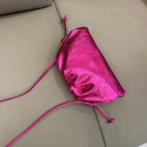 Detailed top view of rose pink dumpling bag with metallic texture on a leather sofa