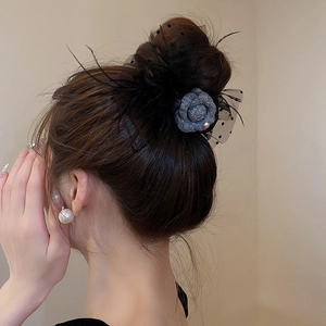Detail of tweed flower hair claw with black lace mesh and elegant feather accents