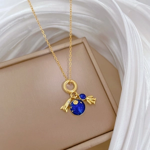 Detail of golden space-themed necklace with rocket, astronaut and blue planet pendants