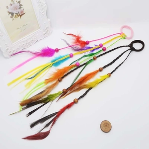 Detail of bohemian kids hair ties with colorful beads and vibrant feathers on white surface