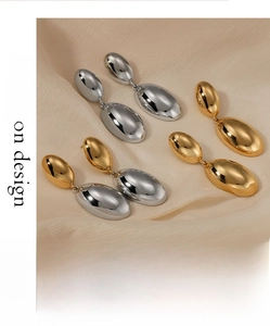 Polished stainless steel waterdrop earrings in gold and silver on silk background