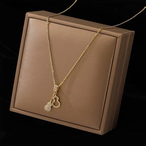 Detail of gold double gourd necklace with micro-pave diamonds on a brown display case