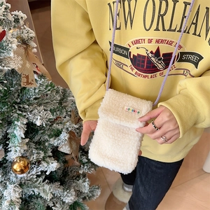 Close-up of plush white lamb wool phone bag featuring colorful label and purple rope strap