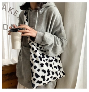 Detail of soft faux fur crossbody bag with black and white cow print for autumn style