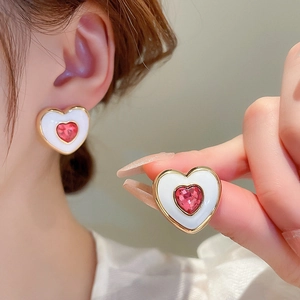 Detailed view of heart-shaped earrings with pink crystals and gold-plated borders