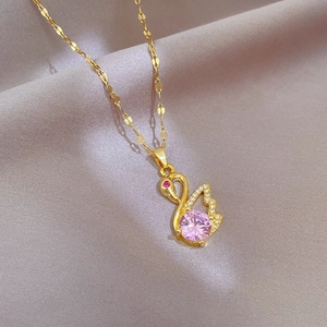 Close-up of golden swan pendant with pink gemstone and crystals on soft silk