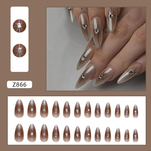 Close-up of almond-shaped press-on nails with brown cat-eye gradient and silver star design